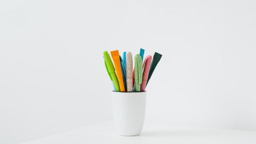 Colorful pens arranged in a white ceramic holder, perfect for office or creative space.